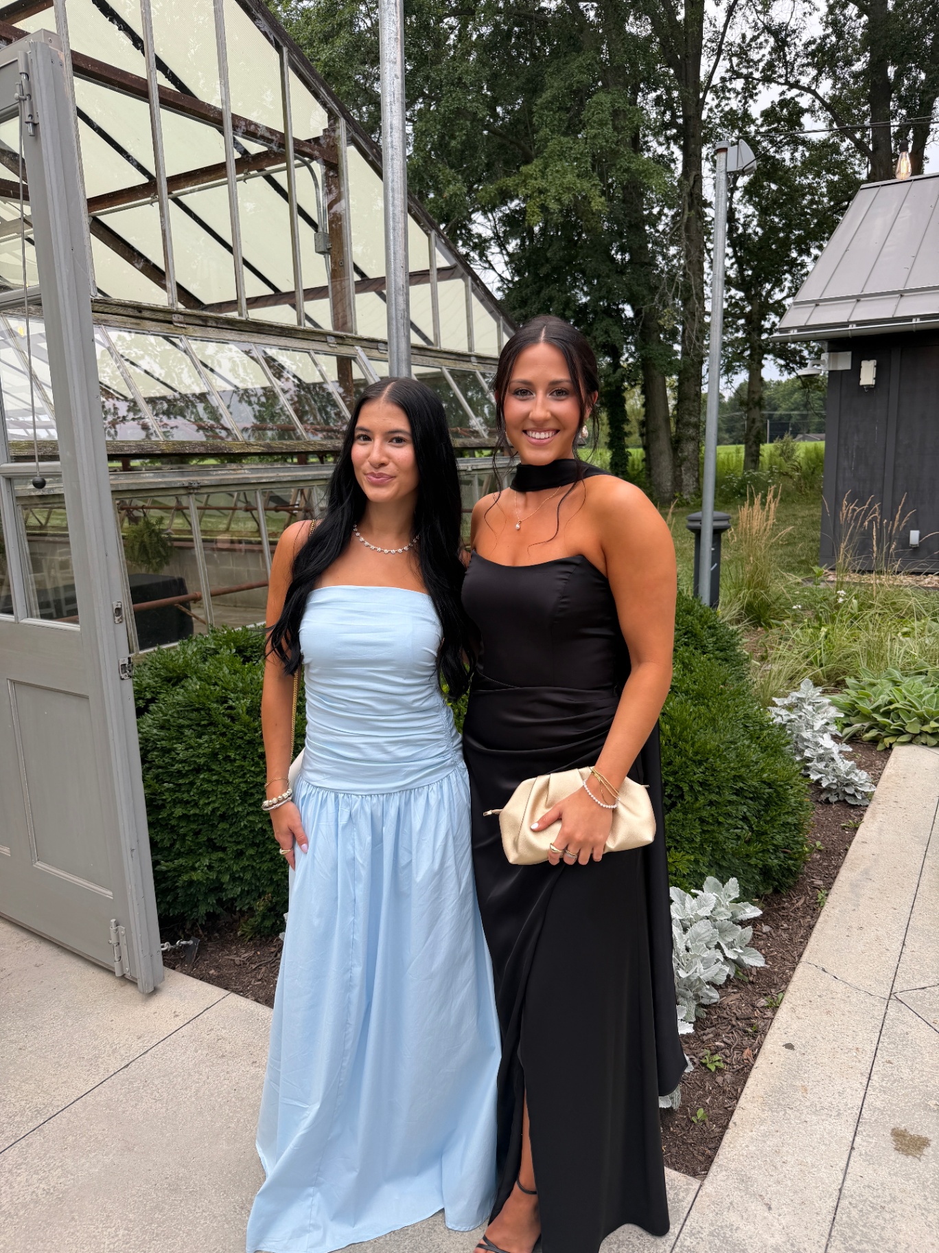 Two Bronze Room clients in formal gowns with warm, even glows at a greenhouse venue