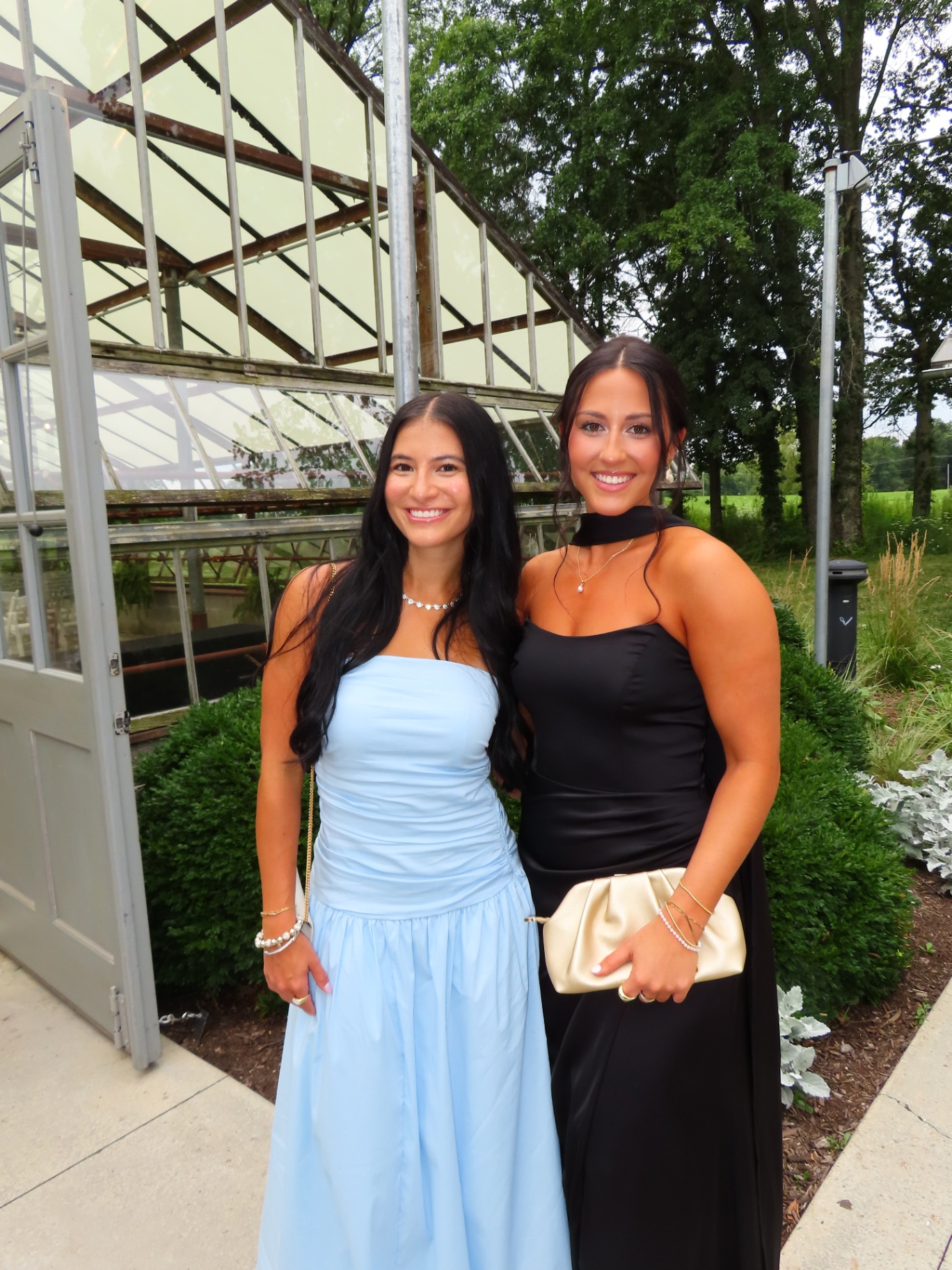 Wedding guests smiling with natural-looking bronzed skin in blue and black gowns