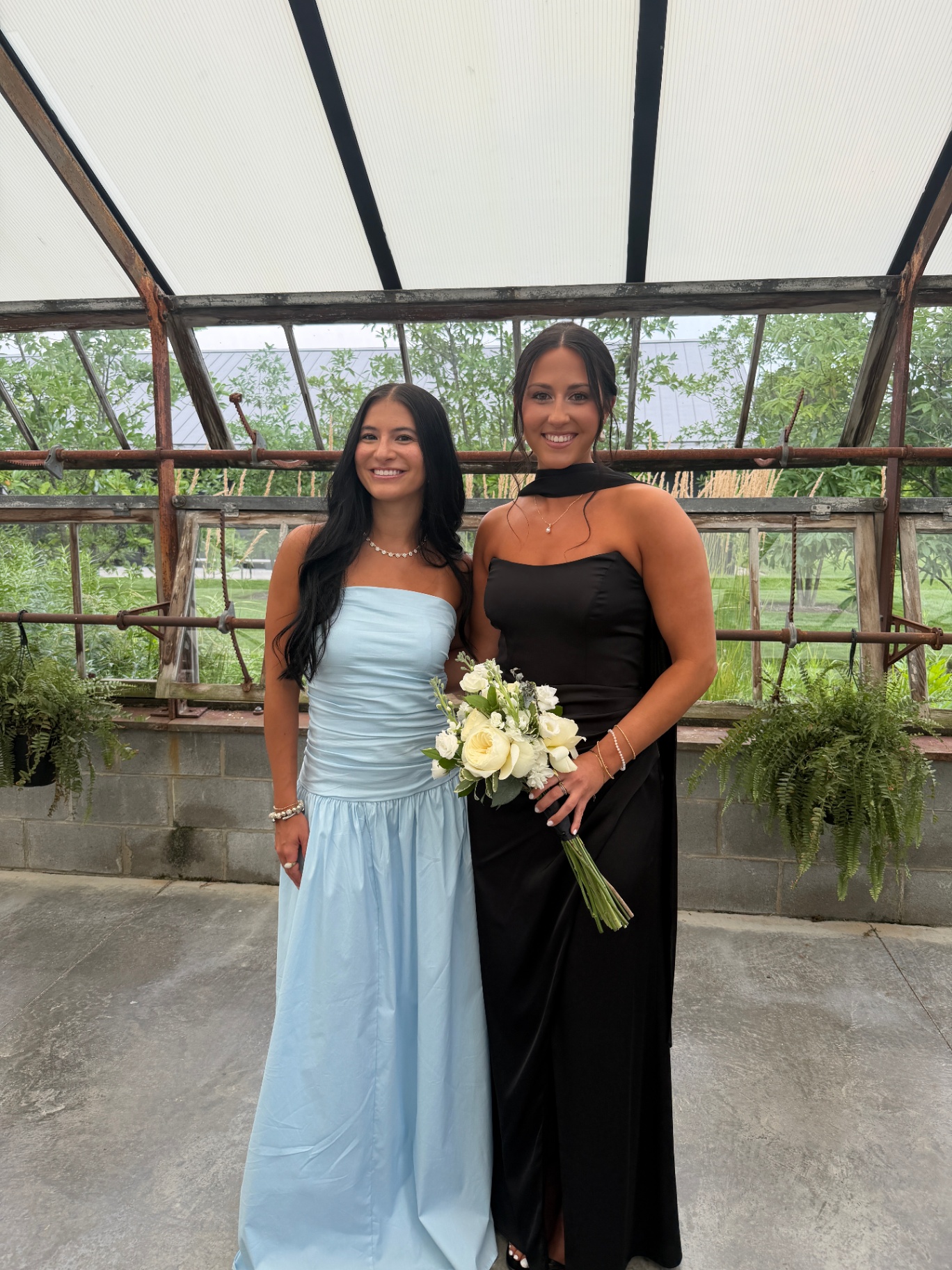 Bridesmaids with streak-free tans holding a white rose bouquet