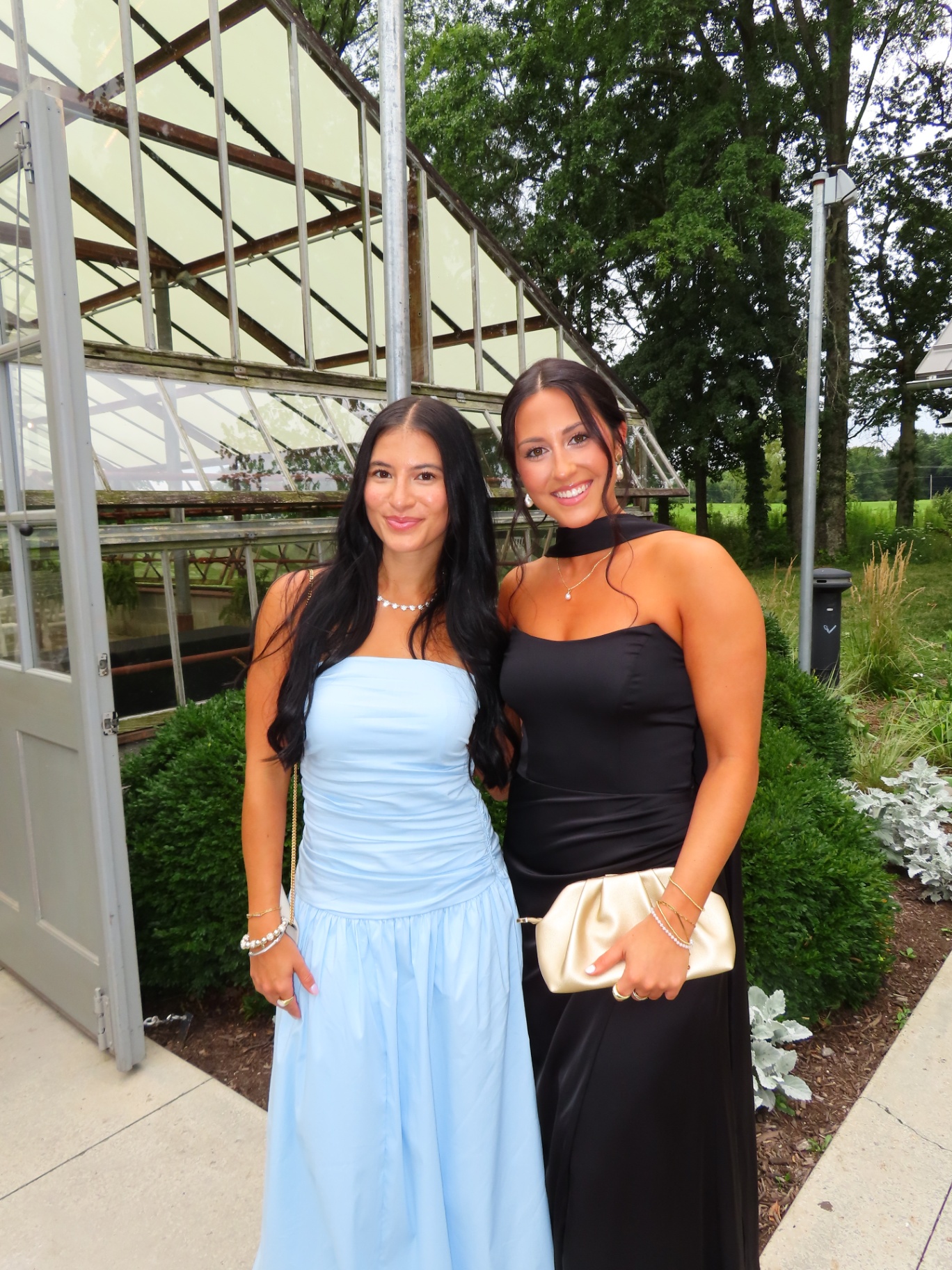 Bronze Room clients glowing in floor-length dresses outside a glass greenhouse